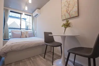 a small bedroom with a bed and a table and chairs at \u6771\u4e0a\u91ce\u306e\u96a0\u308c\u5bb6 \u4e0a\u91ce\u99c5\u5f92\u6b69\u570f\u5185\u306e\u30a2\u30c3\u30c8\u30db\u30fc\u30e0\u306a\u5bbf EoE6 SioE in Tokyo