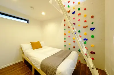 a bedroom with a climbing wall with a bed and a ladder at Shinjuku-Nakano Residence -\u6771\u4e2d\u91ce\u30de\u30f3\u30b9\u30ea\u30fc\u30cf\u30a6\u30b9 - 3\u968e\u5efa\u3066\u5c4b\u4e0a\u4ed8\u304d\u306e1\u68df\u8cb8\u3057\u5207\u308a - \u6700\u59277\u540d in Tokyo