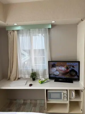 a room with a desk with a television and a window at Shinjuku\u5bbf in Tokyo