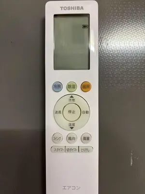 a white remote control with buttons on a wall at Shinjuku\u5bbf in Tokyo
