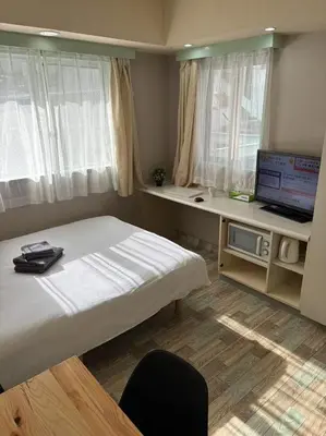 a bedroom with a bed and a television and a desk at Shinjuku\u5bbf in Tokyo