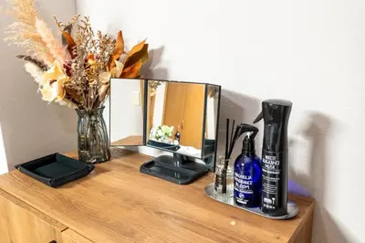 a table with a mirror and some bottles and flowers at Za086 \u67cf\u539f\u30d3\u30eb101 in Tokyo