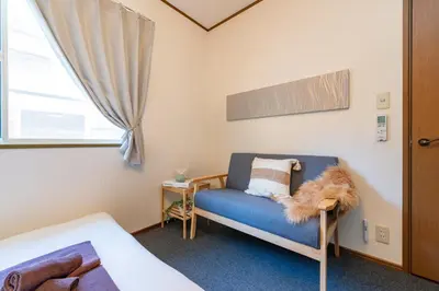 a bedroom with a blue couch and a window at Vivere in Tokyo