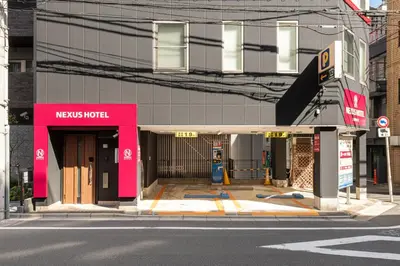 a news hotel with a pink facade on a street at NEXUS HOTEL Gotanda WEST in Tokyo