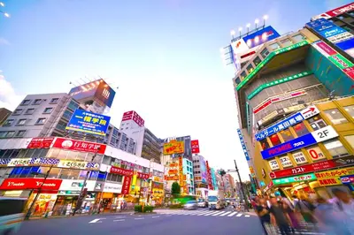 a busy city street with tall buildings and people crossing the street at \u9ad8\u7530\u99ac\u5834 4\u4eba\u53efa2 in Tokyo