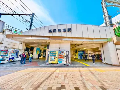 a gas station with people standing outside of it at \u9ad8\u7530\u99ac\u5834 4\u4eba\u53efa2 in Tokyo