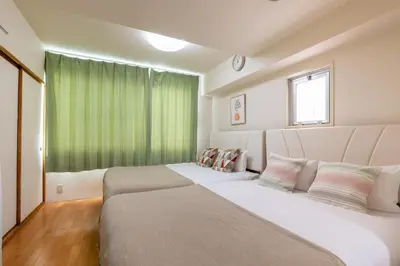 two beds in a room with a green curtain at \u6771\u771f\u30d3\u30eb3f in Tokyo