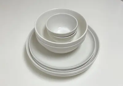 a stack of white bowls and plates on a table at \u6771\u771f\u30d3\u30eb3f in Tokyo