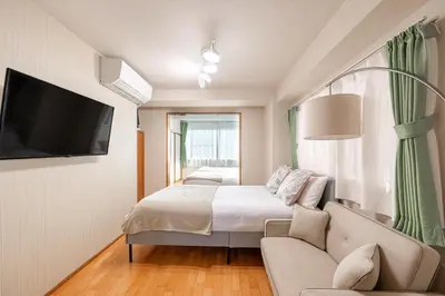 a bedroom with a bed and a couch and a tv at \u6771\u771f\u30d3\u30eb3f in Tokyo