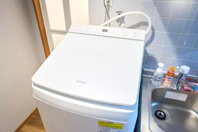 a white toilet in a bathroom next to a washing machine at O-JR \u9ad8\u7530\u99ac\u5834 5mins walk Guest House! New open! Wi-fi! Shinjyuku Waseda area in Tokyo