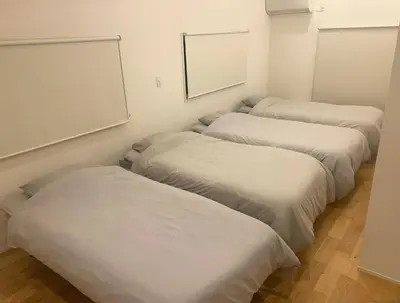 four beds in a room with white sheets at NOIL 2 \u6c60\u888b Ikebukuro \u6c60\u888b\u99c5\u5f92\u6b6914\u5206 \u690e\u540d\u753a\u99c5\u5f92\u6b695\u5206 in Tokyo