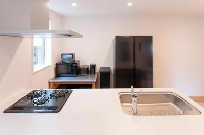 a kitchen with a sink and a black refrigerator at NOIL 2 \u6c60\u888b Ikebukuro \u6c60\u888b\u99c5\u5f92\u6b6914\u5206 \u690e\u540d\u753a\u99c5\u5f92\u6b695\u5206 in Tokyo