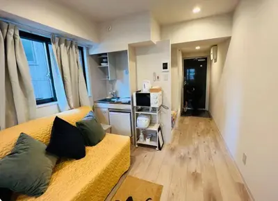 a living room with a yellow couch and a kitchen at ShinjukuLion in Tokyo