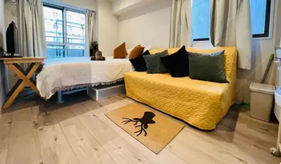 a bedroom with a bed and a yellow couch at ShinjukuLion in Tokyo
