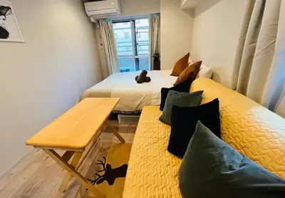 a room with two beds and a table and a couch at ShinjukuLion in Tokyo