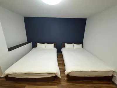 two beds in a room with a blue wall at \u548c\u306e\u6953cottage\u7b2c\u4e8c301 \u65b0\u5bbf\u6b4c\u821e\u4f0e\u753a\u8fd1\u96a3 in Tokyo
