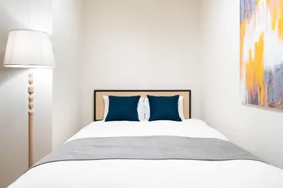 a white bedroom with a bed with blue pillows at Uvas\u6c60\u888b in Tokyo