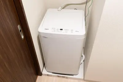 a washing machine in the corner of a room at Uvas\u6c60\u888b in Tokyo