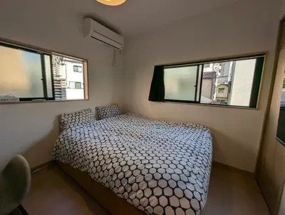 a small bedroom with a bed and two windows at Yahiro House in Tokyo