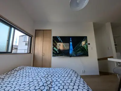 a bedroom with a bed and a tv on the wall at Yahiro House in Tokyo