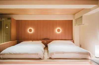 two beds in a bedroom with wooden walls at Hotel Matoma in Tokyo