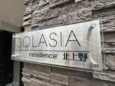 a sign on the side of a stone wall at SOLASIA residence \u5317\u4e0a\u91ce402 in Tokyo