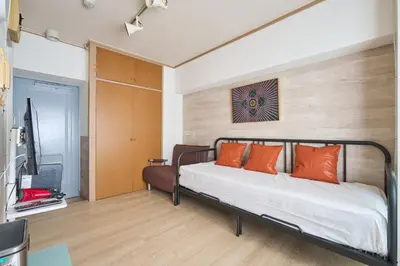 a bedroom with a bed with orange pillows and a television at ND-307Yamanote Line shinjuku \u9ad8\u7530\u99ac\u5834 5mins walk Hostel!\u9ad8\u901fWi-fi! Waseda in Tokyo