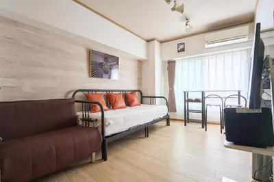 a bedroom with a bed with orange pillows and a couch at ND-307Yamanote Line shinjuku \u9ad8\u7530\u99ac\u5834 5mins walk Hostel!\u9ad8\u901fWi-fi! Waseda in Tokyo