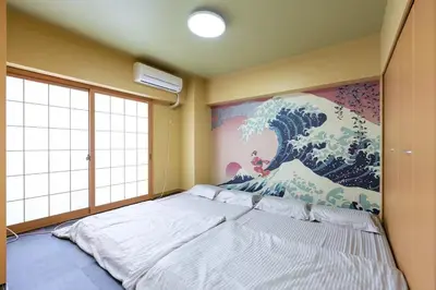 a bed in a room with a painting on the wall at \u5409\u7965\u5929 in Tokyo