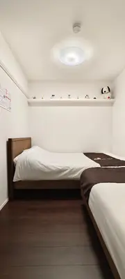 a bedroom with two beds and a white wall at Takasago Utopia Hotel in Tokyo