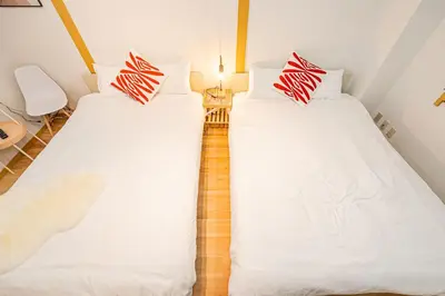 two beds in a room with white and red pillows at Aurora1 in Tokyo