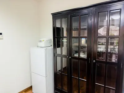 a wooden cabinet with glass doors next to a refrigerator at \u98a8\u82b1Fuka\u6c11\u6cca\u5927\u68ee\u897f002 in Tokyo