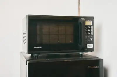a microwave oven sitting on top of a refrigerator at \u548c\u6c23\u4f1a\u3005\u66f3\u821f Wakiaiai Hikihune in Tokyo