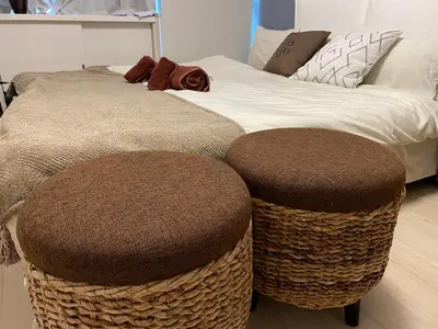 a bed with two brown ottomans next to a bed at Bali Haven Yotsuya \u30d0\u30ea\u306e\u96a0\u308c\u5bb6 \u56db\u8c37\u99c5\u5f92\u6b697\u5206\u30c0\u30d6\u30eb\u30d9\u30c3\u30c81R in Tokyo