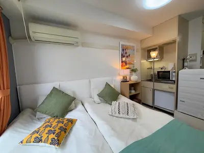 a small bedroom with a white bed with green pillows at Shinjuku Yotsuya Sanchome Station 7-minute walk Hawaiian Twin Bed Charm Room 1R in Tokyo