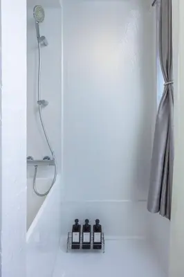 a shower in a white bathroom with three bottles at Natsumezaka Room1 NM1 in Tokyo