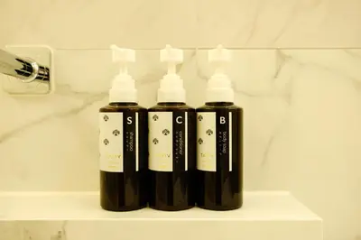 three bottles of black liquid sitting on a shelf in a bathroom at Roppongi House by U - Designers room - Steps to Roppongi Hills & Nightlife in Tokyo