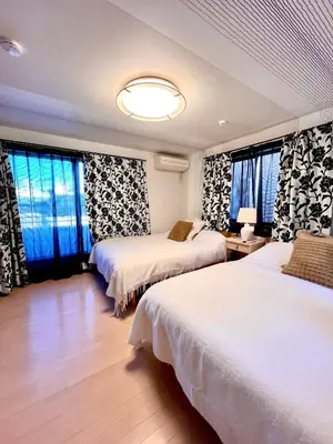 a hotel room with two beds and windows at Dragon\u4e09\u5c42\u522b\u5885 \u65b0\u5bbf \u6da9\u8c37 \u4e0a\u91ce\u5546\u5708 \u5c71\u624b\u7ebf\u8f66\u7ad98\u5206\u949f \u4ea4\u901a\u4fbf\u5229 in Tokyo