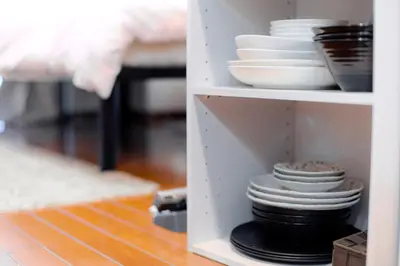 a white shelf with plates and bowls on it at Luna House in Tokyo