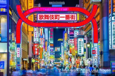 a busy city street with a red sign in the middle at Luna House in Tokyo