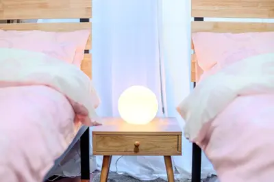 a white lamp on a table between two beds at Luna House in Tokyo