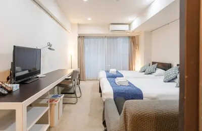 a room with two beds and a desk with a television at Pangoo Shinagawa Room 202 - Vacation STAY 98591v in Tokyo
