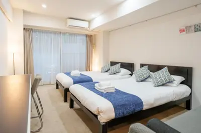 a bedroom with three beds with blue and white pillows at Pangoo Shinagawa Room 402 - Vacation STAY 99354v in Tokyo