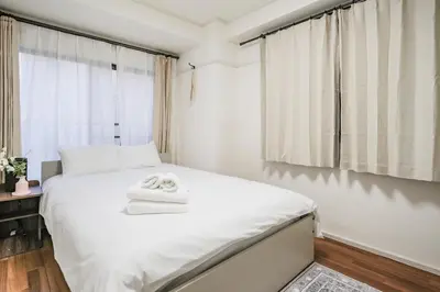 a bedroom with a bed with two towels on it at Ikebukuro La Rêve House in Tokyo