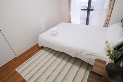 a bedroom with a white bed and a window at Ikebukuro La Rêve House in Tokyo