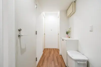 a white bathroom with a toilet and a door at Ikebukuro La Rêve House in Tokyo