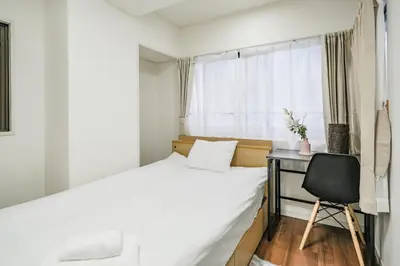 a bedroom with a bed and a desk and a chair at Ikebukuro La Rêve House in Tokyo