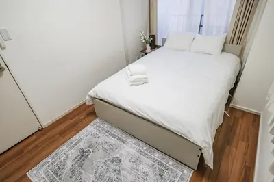 a small bedroom with a white bed and a rug at Ikebukuro La Rêve House in Tokyo