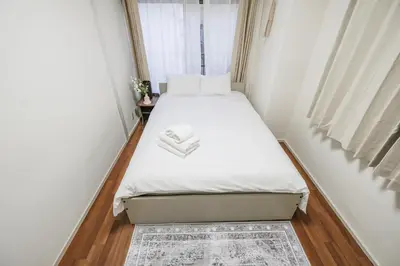 a small bedroom with a bed with white sheets at Ikebukuro La Rêve House in Tokyo