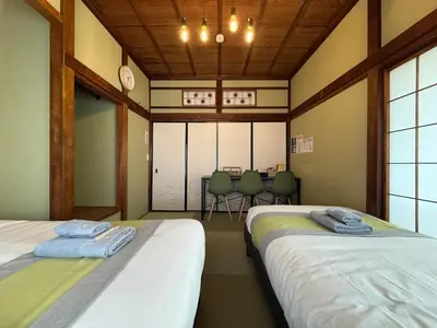 two beds in a room with a table and chairs at nestay villa tokyo ueno in Tokyo